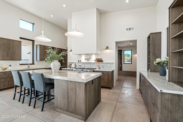 kitchen with pendant lighting, a wealth of natural light, a kitchen breakfast bar, and a high ceiling