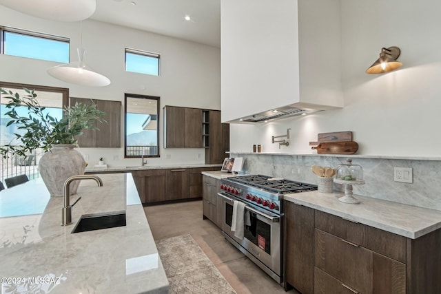 kitchen with double oven range, a towering ceiling, sink, and custom range hood