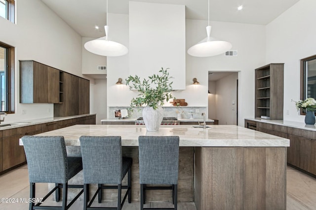 kitchen featuring pendant lighting, an island with sink, a breakfast bar area, and a high ceiling