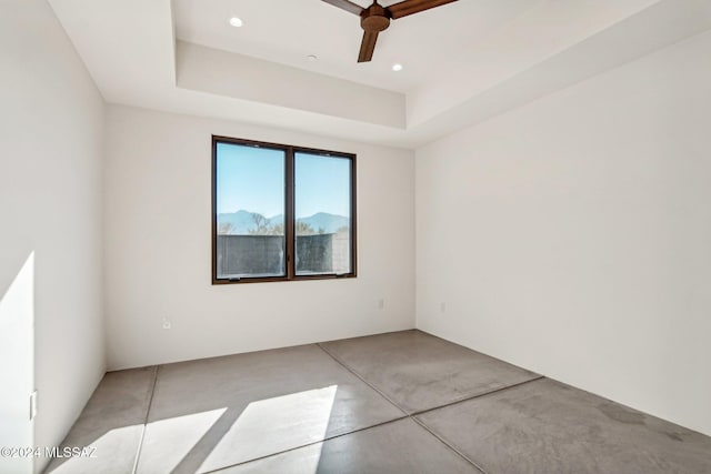 unfurnished room featuring a raised ceiling and ceiling fan