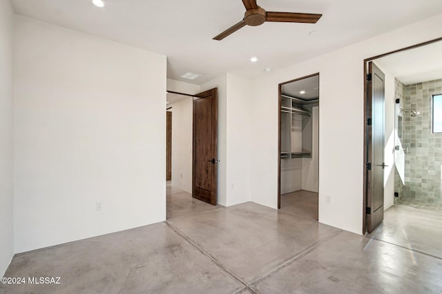 unfurnished bedroom featuring connected bathroom, a spacious closet, a closet, and ceiling fan