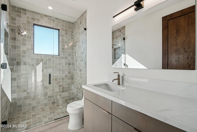 bathroom featuring vanity, toilet, and a shower with door