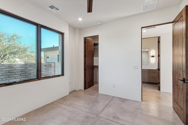 unfurnished bedroom featuring ensuite bathroom, a walk in closet, and a closet