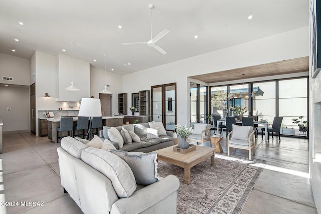 living room with ceiling fan and a towering ceiling