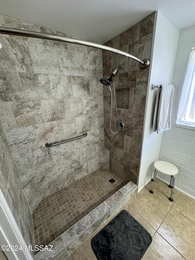 bathroom featuring tile patterned flooring, a tile shower, and a textured ceiling