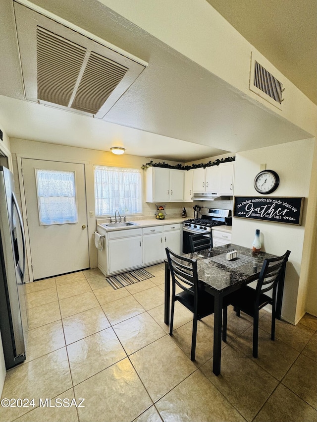 kitchen featuring stainless steel appliances, sink, light tile patterned floors, white cabinets, and range hood