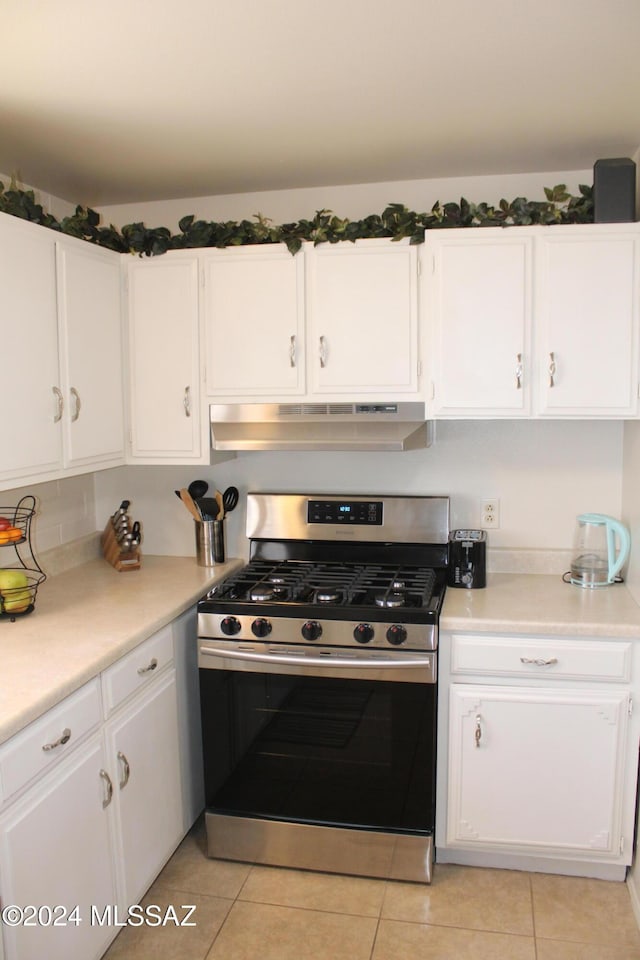 kitchen featuring white cabinets, gas stove, light tile patterned flooring, and extractor fan