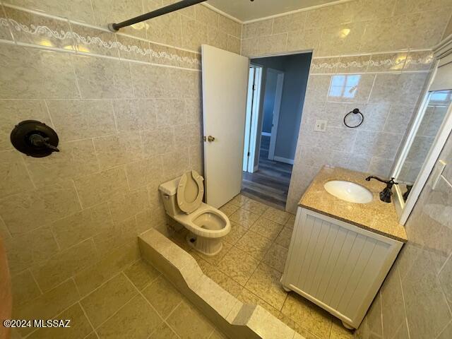 bathroom with vanity, toilet, a shower, and tile walls