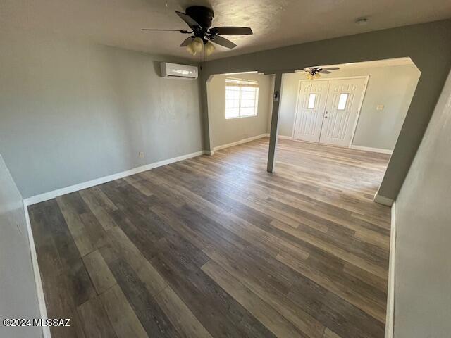 interior space featuring ceiling fan, dark hardwood / wood-style flooring, and a wall mounted air conditioner