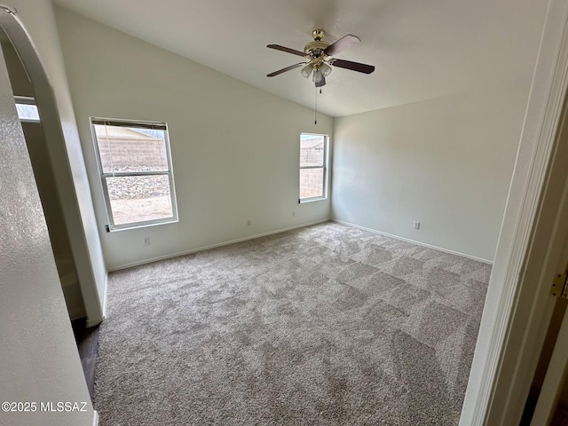 spare room featuring ceiling fan, arched walkways, carpet flooring, baseboards, and vaulted ceiling