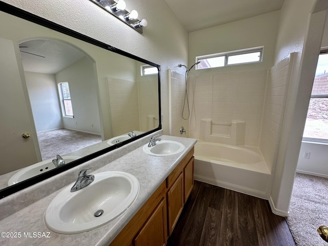 full bathroom with plenty of natural light, a sink, and wood finished floors