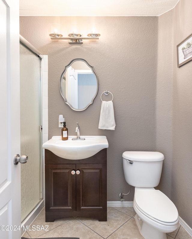 bathroom with tile patterned floors, vanity, toilet, and a shower with door