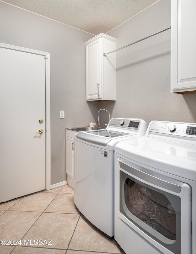 laundry area featuring sink, cabinets, a textured ceiling, light tile patterned flooring, and washer and dryer