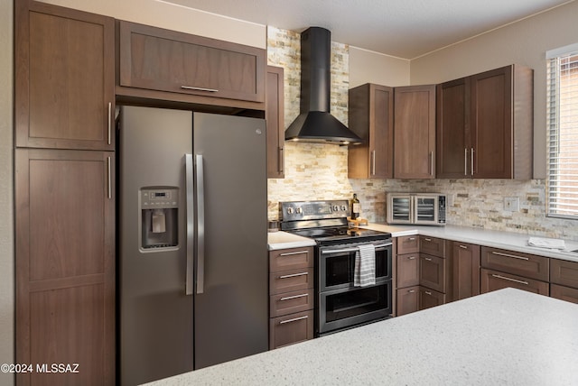 kitchen featuring tasteful backsplash, light stone countertops, wall chimney exhaust hood, and appliances with stainless steel finishes