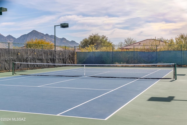 view of tennis court with basketball hoop and a mountain view