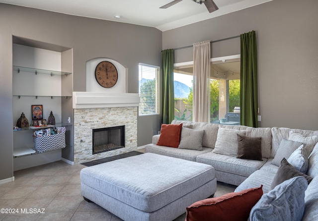 tiled living room with ceiling fan and a fireplace