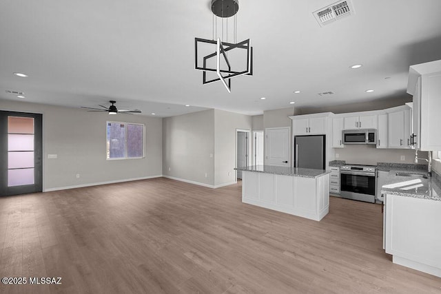 kitchen featuring sink, stainless steel appliances, a kitchen island, white cabinets, and light wood-type flooring