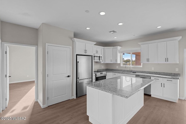 kitchen featuring white cabinetry, a center island, sink, light hardwood / wood-style flooring, and appliances with stainless steel finishes