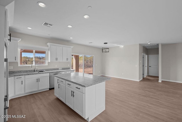 kitchen featuring stainless steel dishwasher, a kitchen island, white cabinetry, and sink