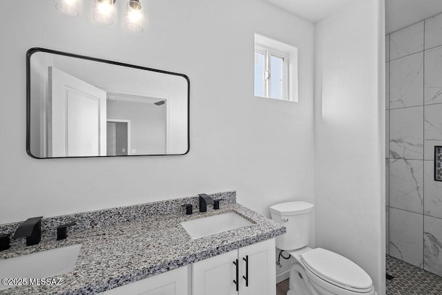 bathroom with a tile shower, vanity, and toilet