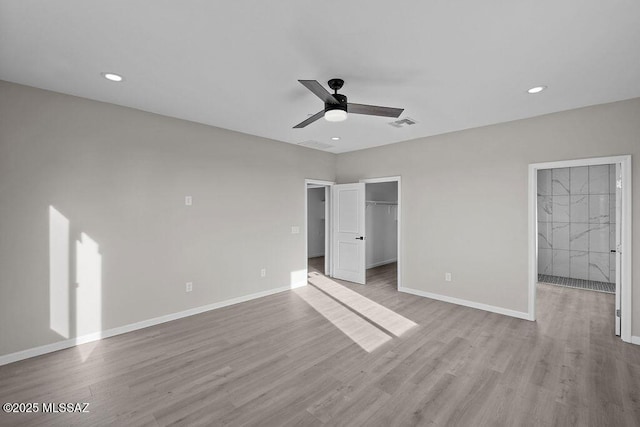 unfurnished bedroom featuring ceiling fan, light wood-type flooring, a spacious closet, and a closet