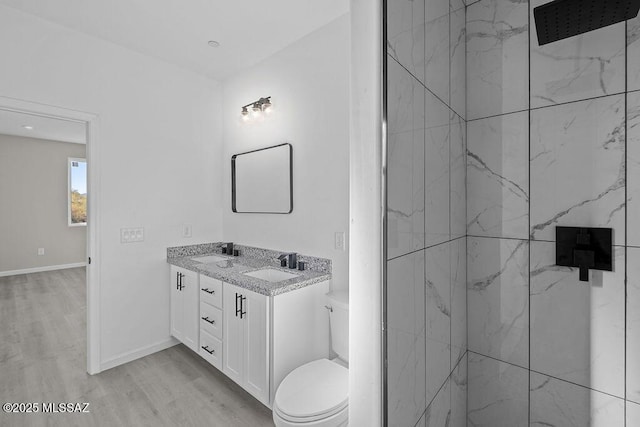 bathroom featuring tiled shower, hardwood / wood-style floors, vanity, and toilet