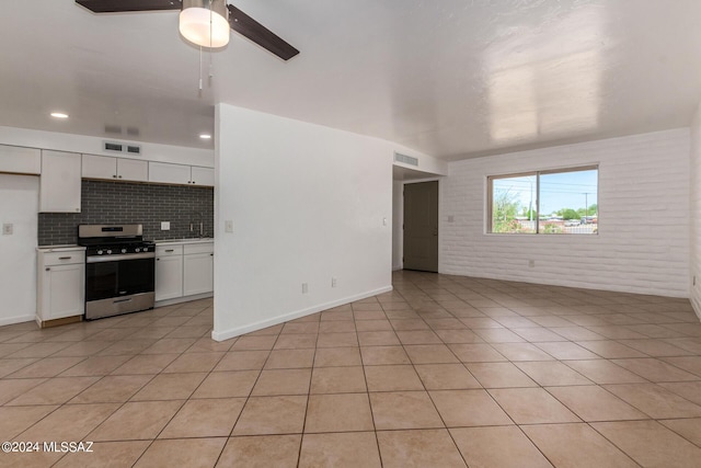 unfurnished living room featuring light tile patterned floors, sink, ceiling fan, and brick wall