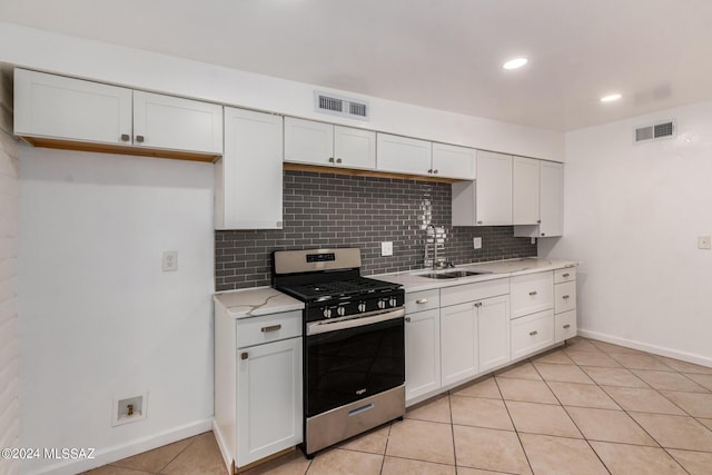 kitchen with decorative backsplash, stainless steel gas range, sink, light tile patterned floors, and white cabinets