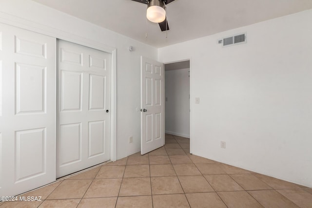 unfurnished bedroom featuring ceiling fan, a closet, and light tile patterned flooring