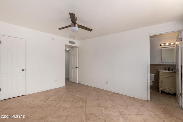 unfurnished bedroom featuring ensuite bathroom, ceiling fan, and light tile patterned flooring