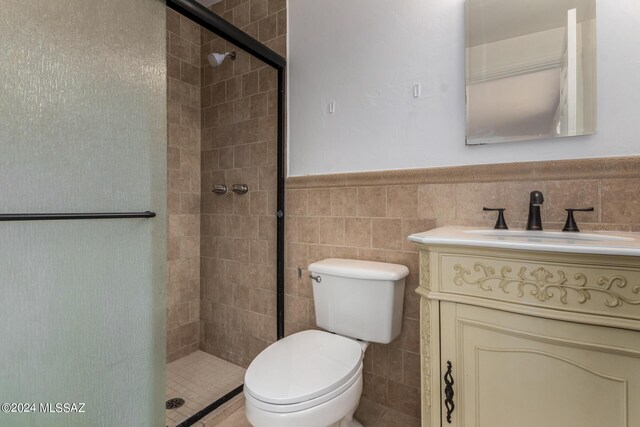 bathroom with vanity, a shower with door, toilet, and tile walls