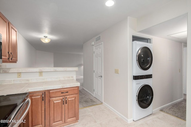 laundry area featuring stacked washer and dryer and light tile patterned floors