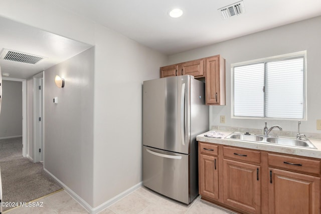 kitchen with light tile patterned floors, sink, and stainless steel refrigerator