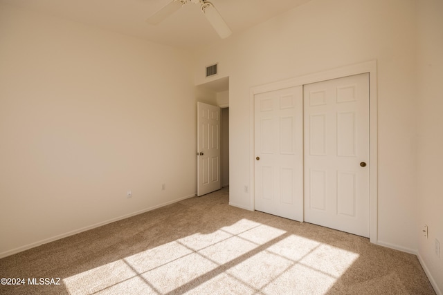 unfurnished bedroom featuring light colored carpet, a closet, and ceiling fan