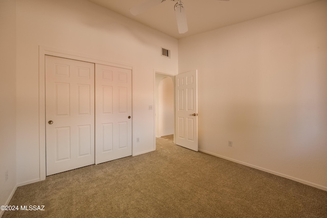 unfurnished bedroom featuring carpet flooring, ceiling fan, and a closet