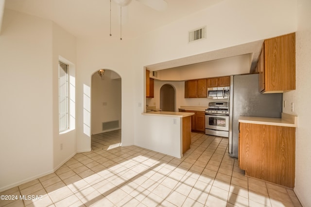 kitchen with ceiling fan, light tile patterned flooring, kitchen peninsula, and stainless steel appliances