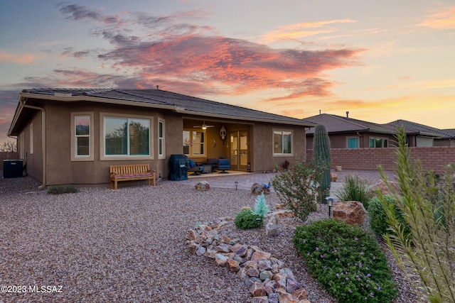 back house at dusk featuring central AC and a patio area