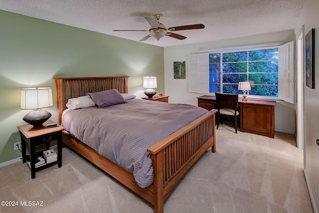 bedroom with a textured ceiling, ceiling fan, and light carpet