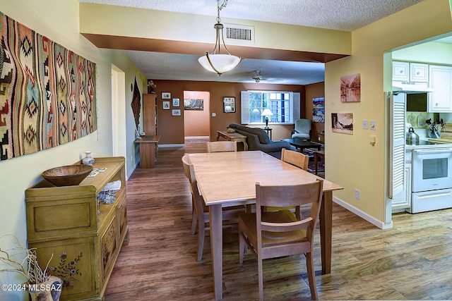 dining space with a textured ceiling and light wood-type flooring