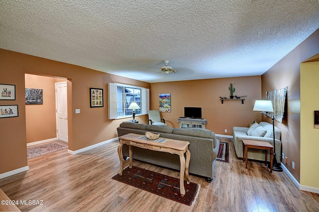 living room with a textured ceiling, hardwood / wood-style flooring, and ceiling fan