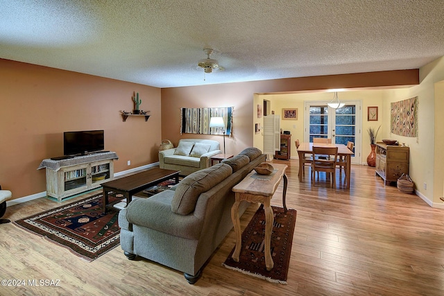 living room featuring ceiling fan, wood-type flooring, and a textured ceiling