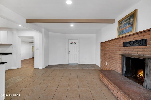 foyer entrance with beamed ceiling, a fireplace, and light tile patterned flooring