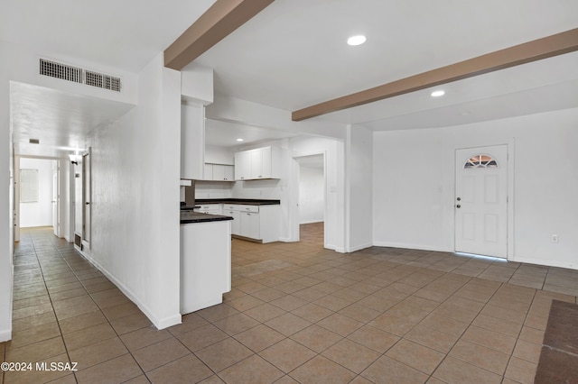 kitchen featuring light tile patterned floors, white cabinetry, and beam ceiling