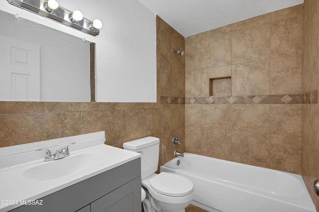 full bathroom with vanity, tiled shower / bath combo, tile walls, and toilet