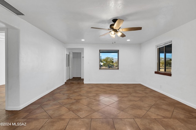 empty room featuring dark tile patterned floors, a wealth of natural light, and ceiling fan