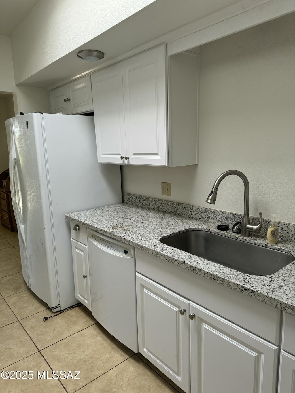 kitchen featuring light stone countertops, white appliances, white cabinetry, and sink