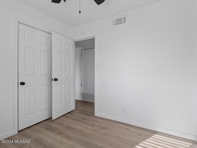 unfurnished bedroom featuring a closet, light hardwood / wood-style floors, and ceiling fan