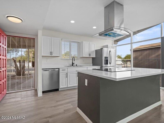 kitchen featuring sink, stainless steel appliances, light hardwood / wood-style flooring, island exhaust hood, and white cabinets