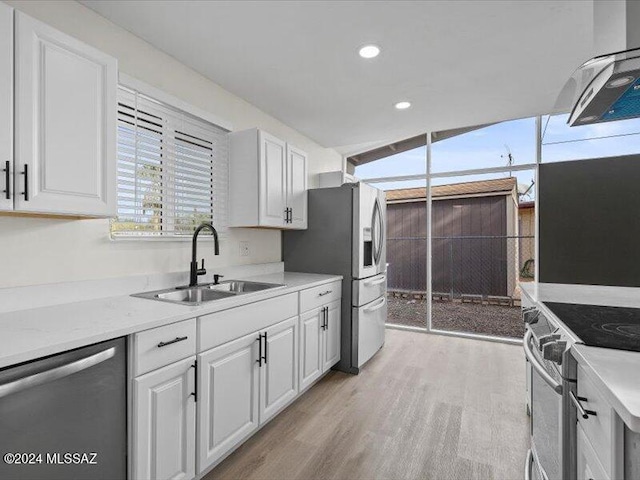 kitchen with white cabinets, sink, light stone countertops, light hardwood / wood-style floors, and stainless steel appliances