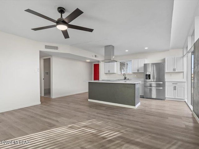 kitchen with light wood-type flooring, sink, stainless steel fridge with ice dispenser, a center island, and white cabinetry